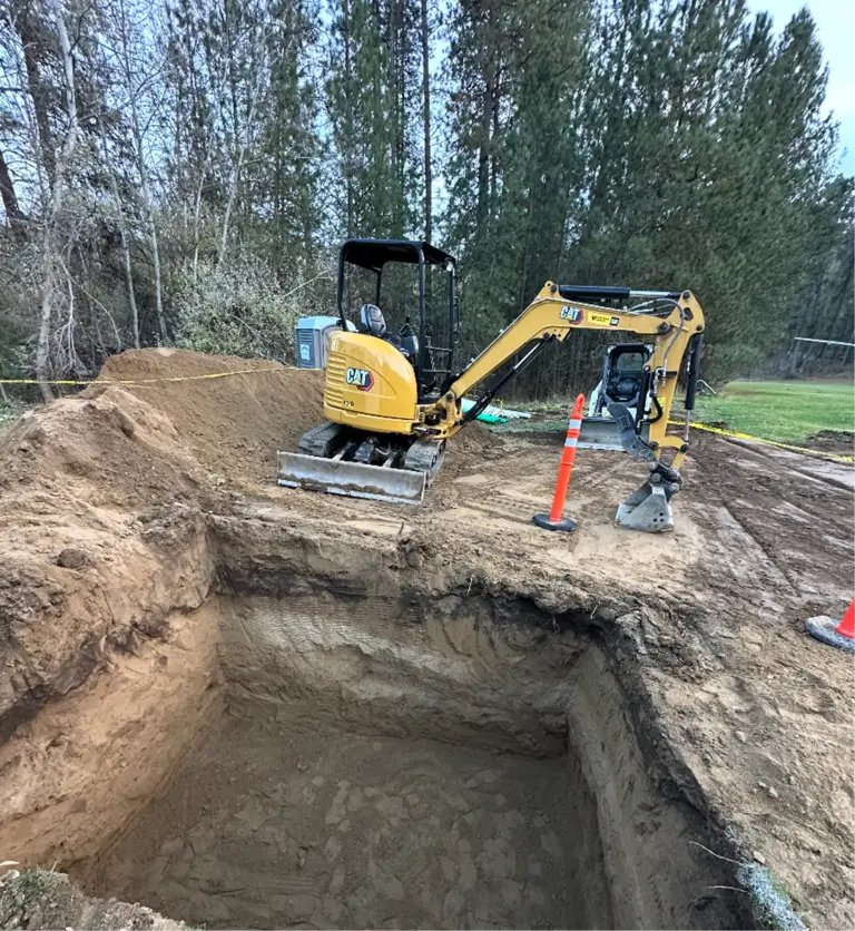 An excavator sitting above a large hole in the ground